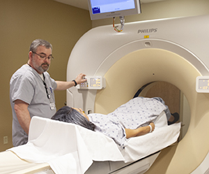 Technician preparing woman for CT scan.