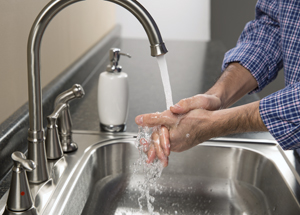 Primer plano de manos en el lavabo debajo de un chorro de agua.